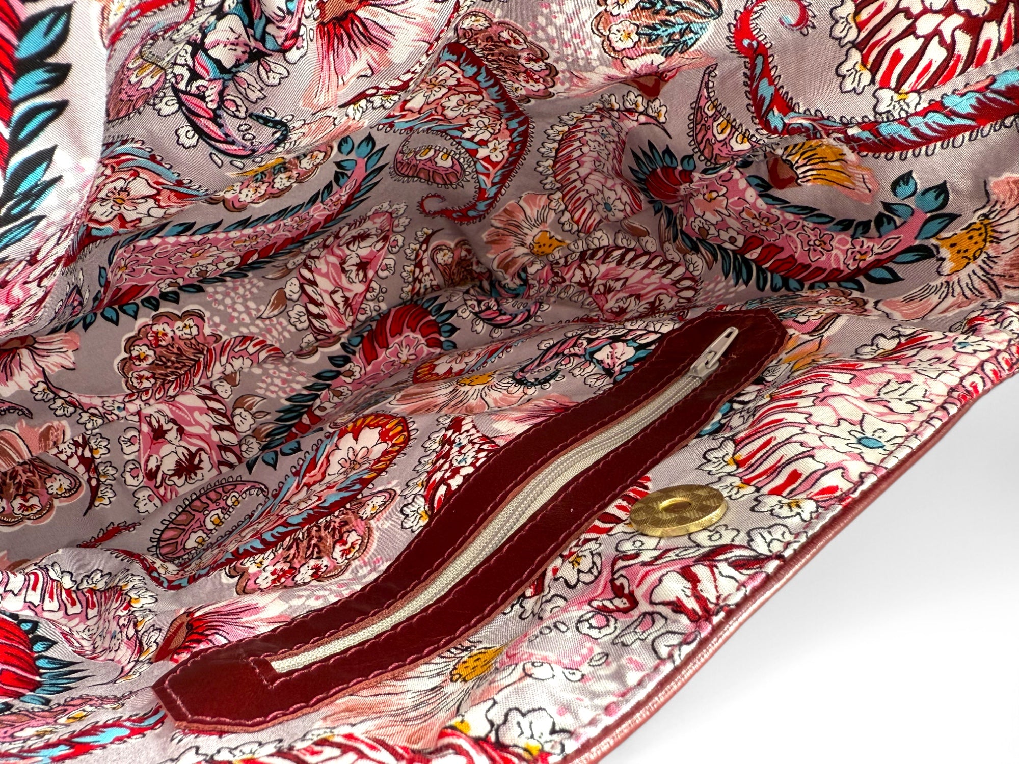 Close-up of a colorful paisley patterned lining of a burgundy leather slouch handbag, highlighting the interior zipper pocket