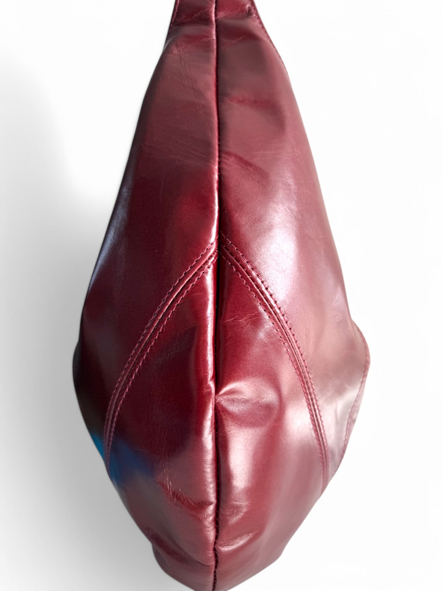 Deep red leather bag, showing the stitching detail on a white background