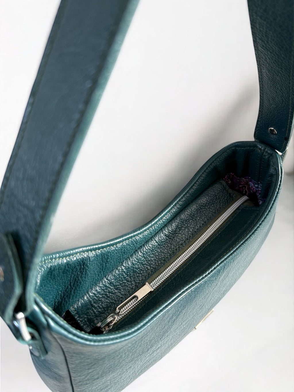 Birds Eye view of the Faye rescued leather handbag in deep teal showing the silver zipper opening at the top of the bag