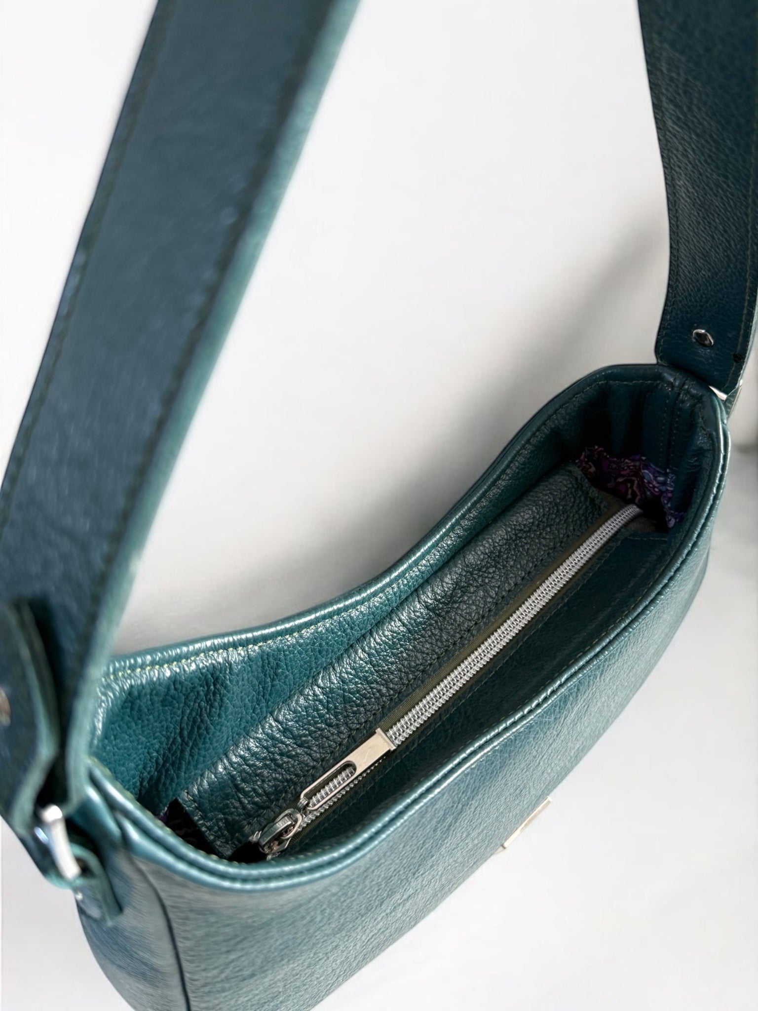 Birds Eye view of the Faye rescued leather handbag in deep teal showing the silver zipper opening at the top of the bag