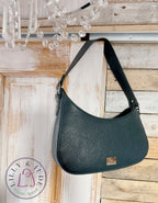 Peacock green leather handbag hanging on a wooden door with a chandelier in the background.