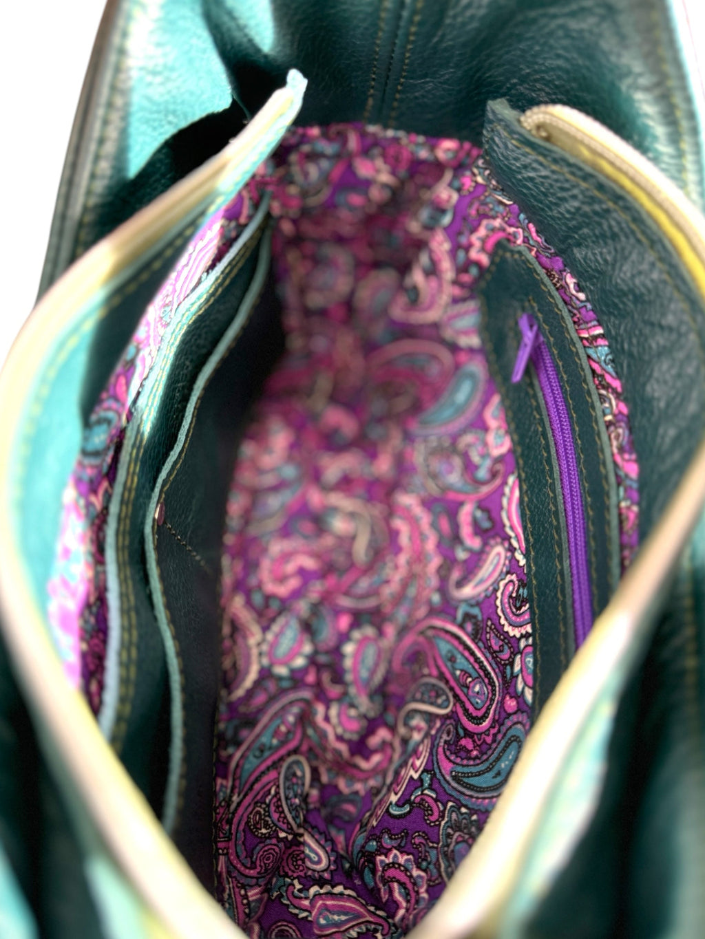 Close-up of a purple paisley fabric lining inside the teal coloured Faye leather bag.