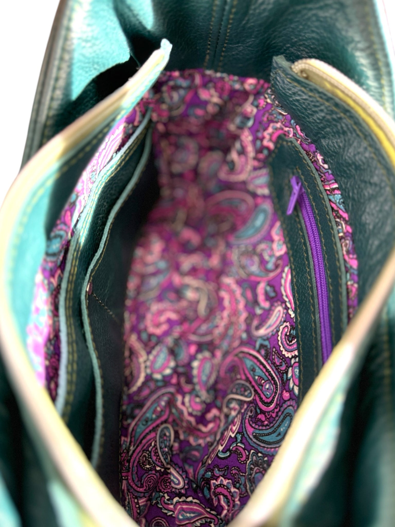 Close-up of a purple paisley fabric lining inside the teal coloured Faye leather bag.