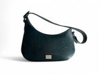 Teal green leather, asymmetric design handbag with silver hardware and a fixed leather strap on a white background