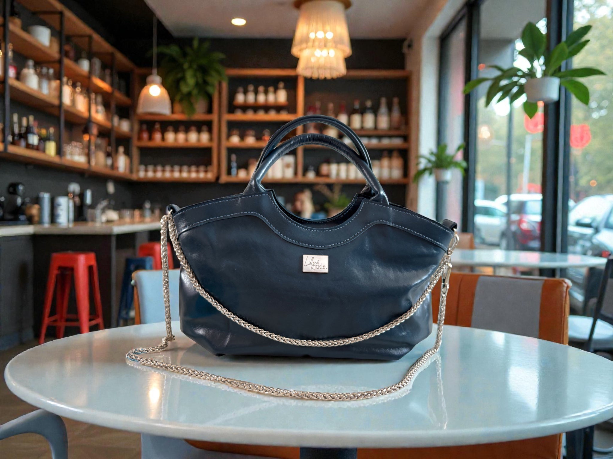 Navy blue leather Flossy handbag with a silver chain detail on a table in a cafe setting