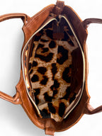 Birds Eye view of the open, brown leather Flossy bag with a leopard print interior on a white background