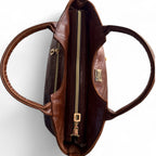 Birds Eye view of the Flossy Handbag, made from chestnut brown leather with gold zipper on a white background. 