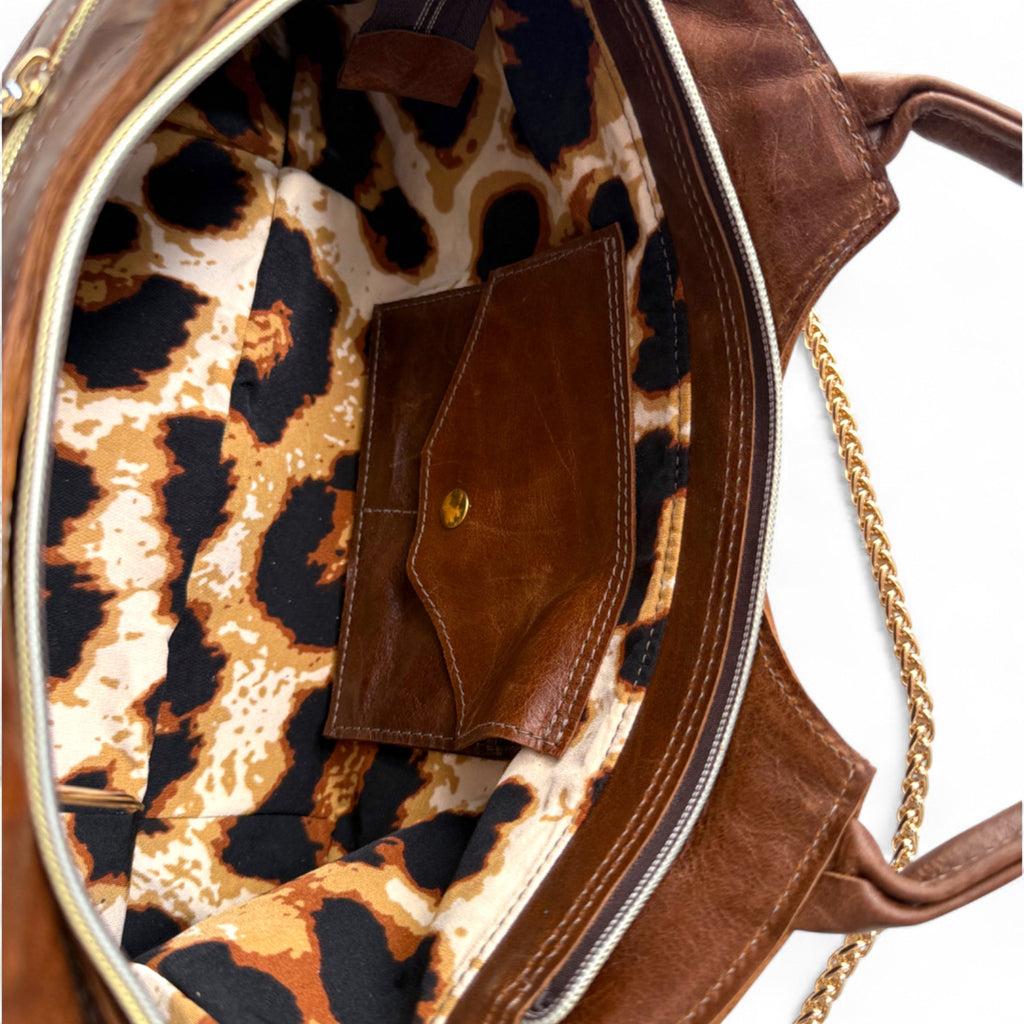 Close up view of the interior of the brown leather Flossy handbag with leopard print interior lining and integrated purse
