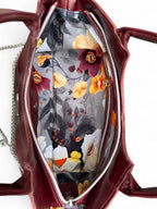 View from above of the Burgundy Flossy handbag, with the zipper open and the grey floral lining showing. 