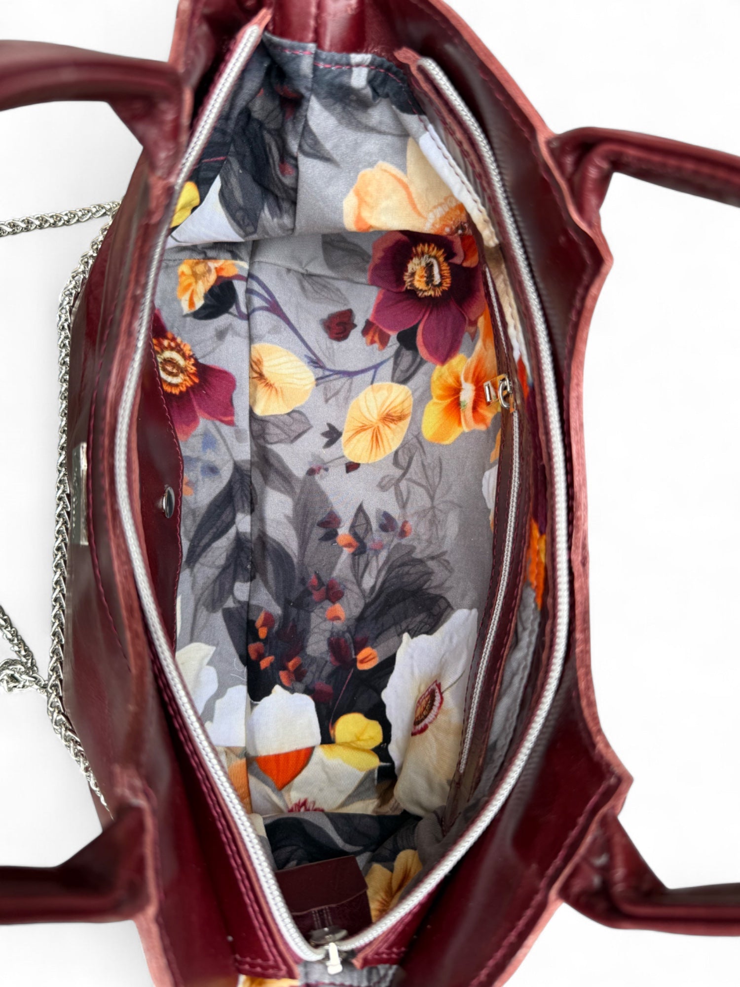 View from above of the Burgundy Flossy handbag, with the zipper open and the grey floral lining showing. 
