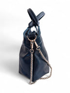 Side view of the navy blue / dark teal rescued leather Flossy handbag with silver hardware and chain detail on a white background