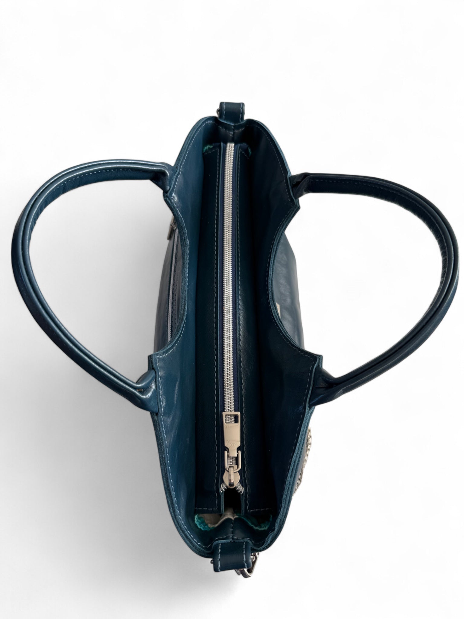 Birds Eye view of the navy blue Flossy bag with silver zipper opening at the top and rolled handles.