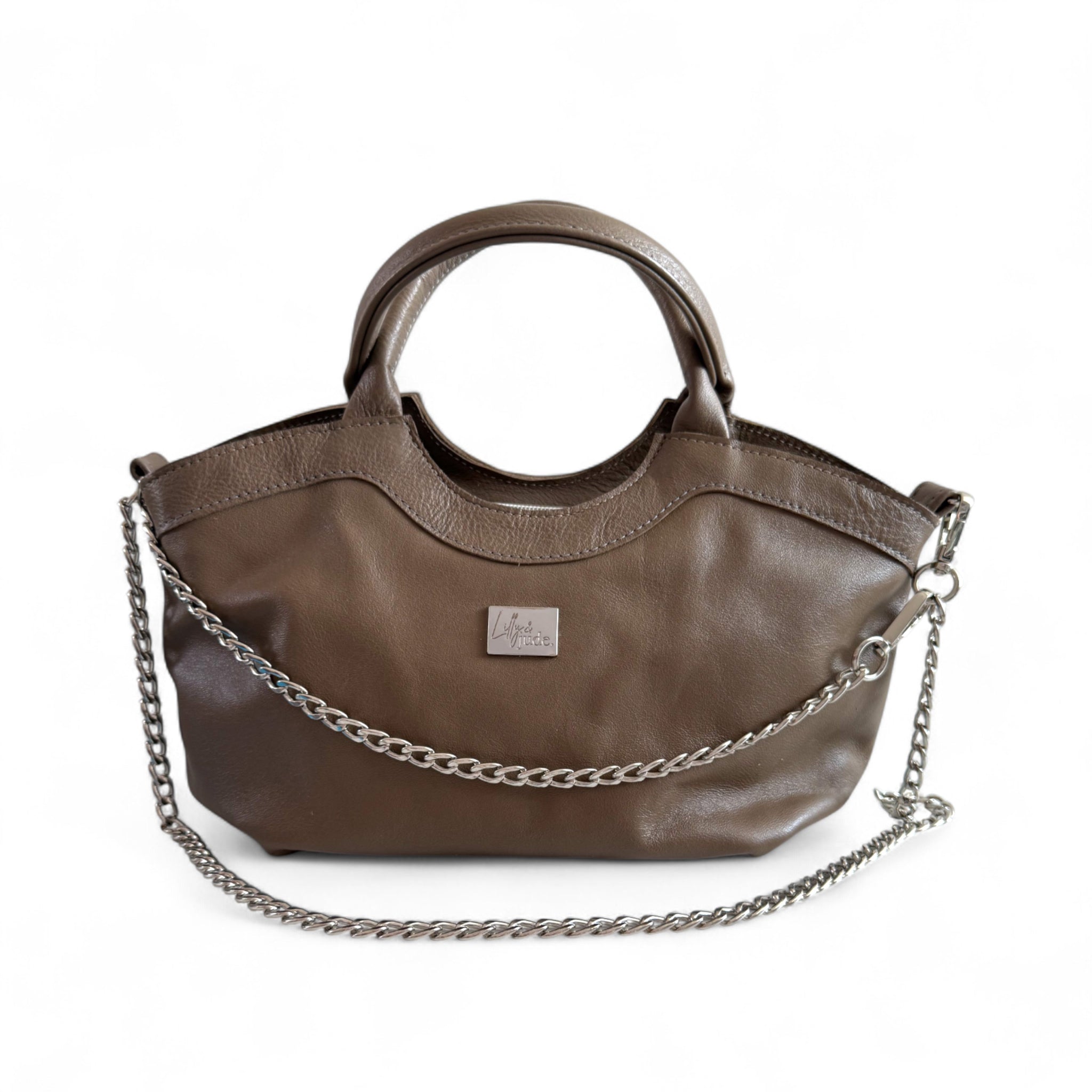 Slouchy, taupe leather handbag, with a silver chain, sitting on a white background. 