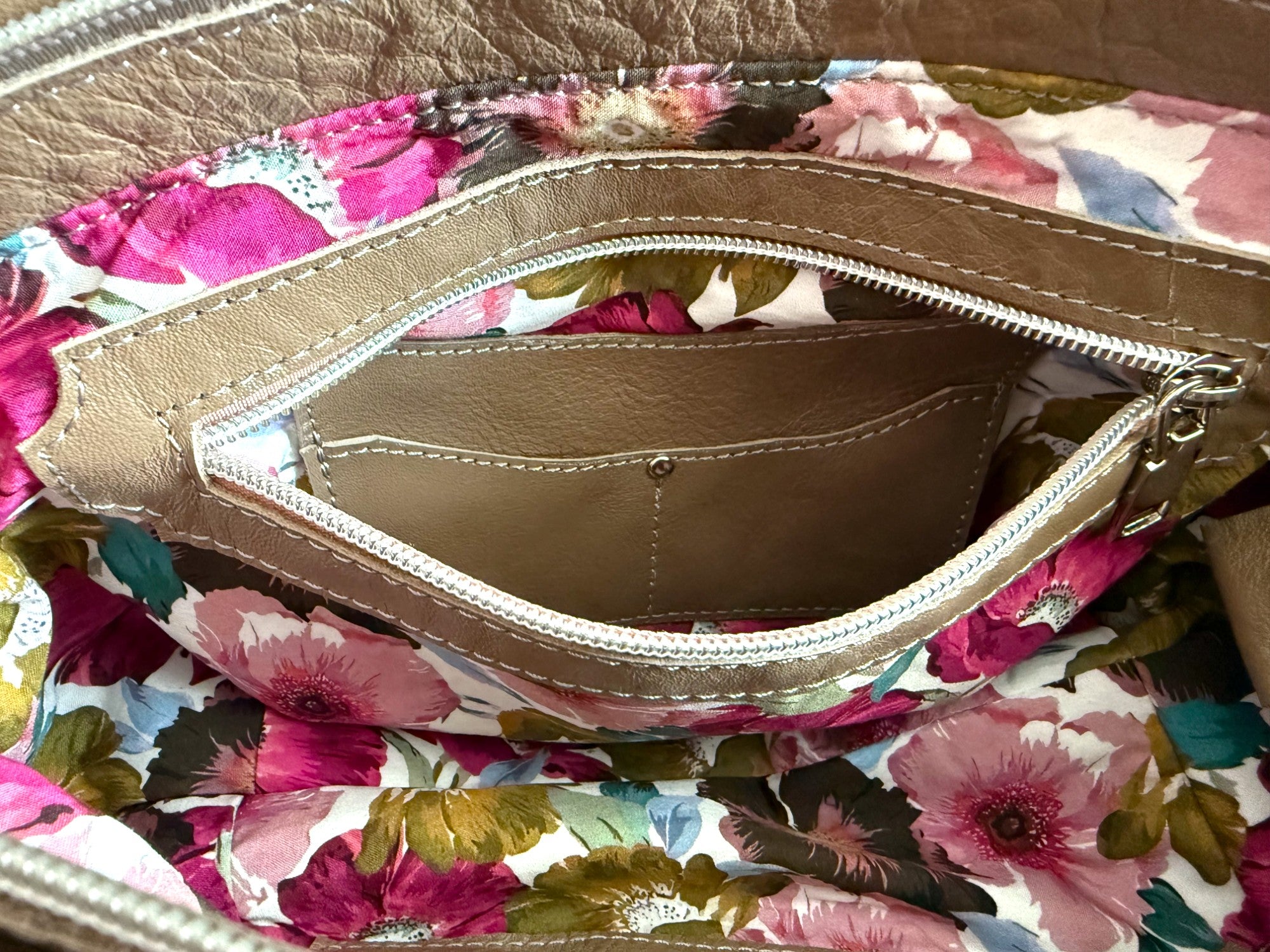 Image shows the floral patterned lining of the Flossy bag with interior zipper pocket open to show the integrated purse.