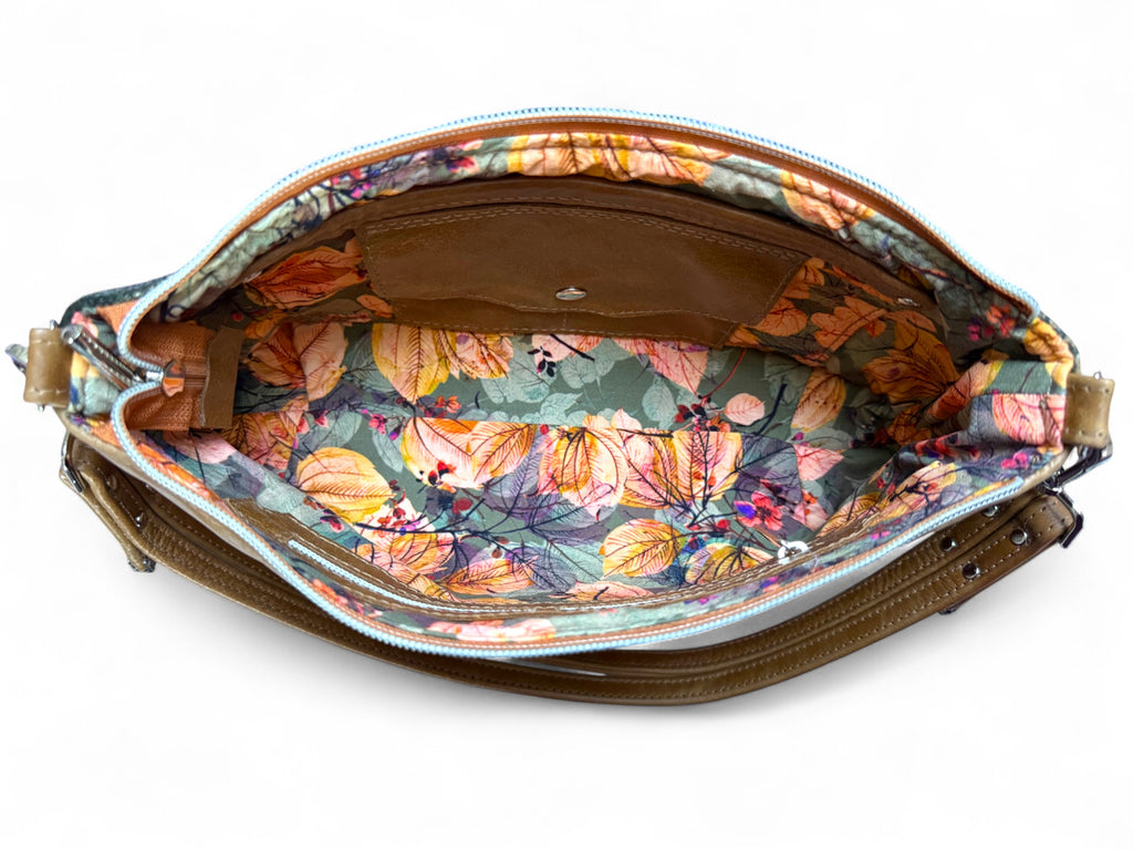 Floral-patterned interior of handbag with a brown leather strap on a white background. 