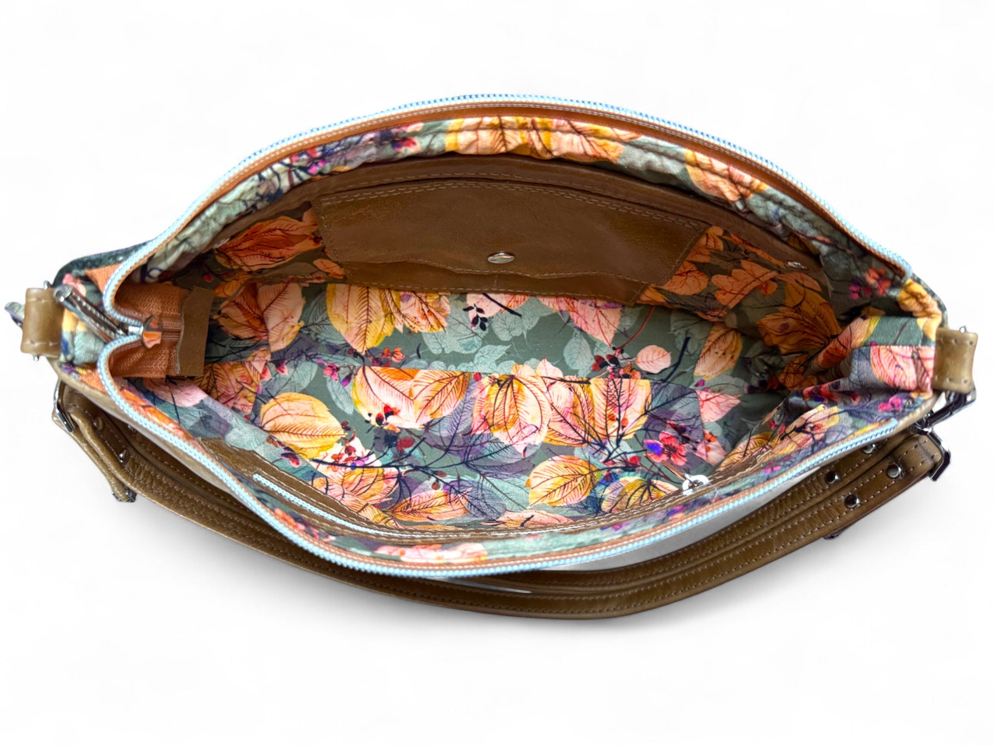 Floral-patterned interior of handbag with a brown leather strap on a white background. 