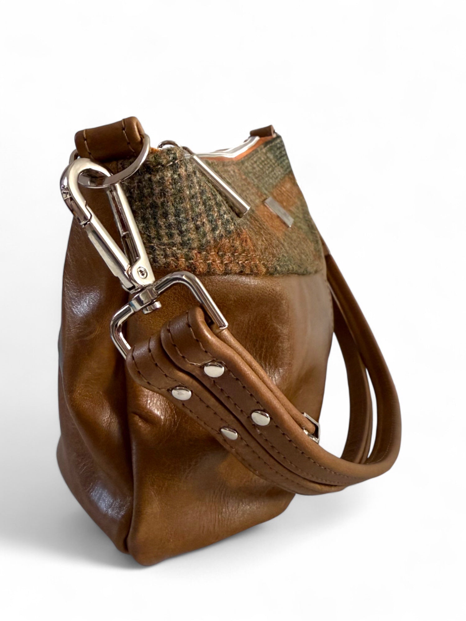 Brown leather handbag with a woollen tweed and silver buckle on a white background