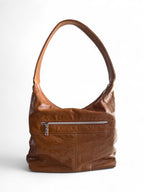 View of a tan brown leather slouchy handbag with a silver zipper on a white background