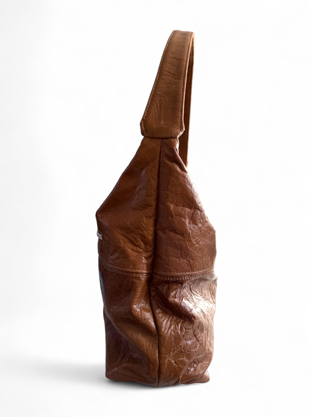 Side view of a tan brown leather slouchy shoulder bag on a white background