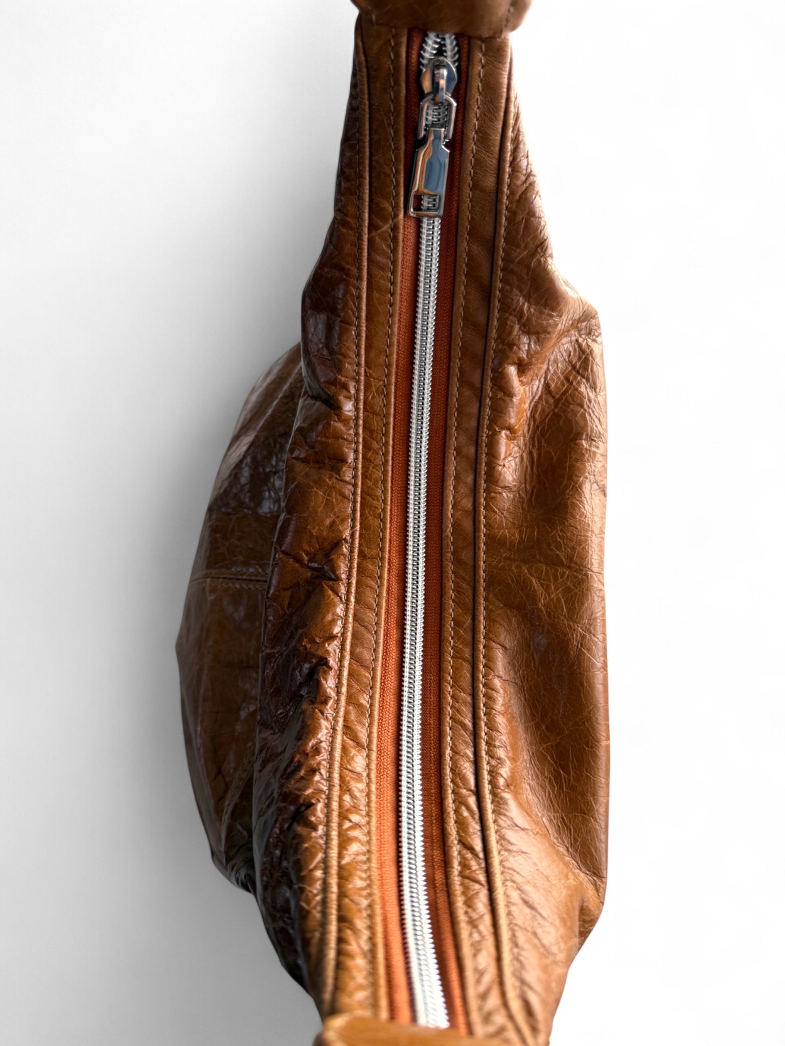 Brown leather bag with a zipper on a white background