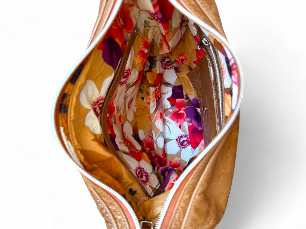 Brown leather bag with floral lining on a white background