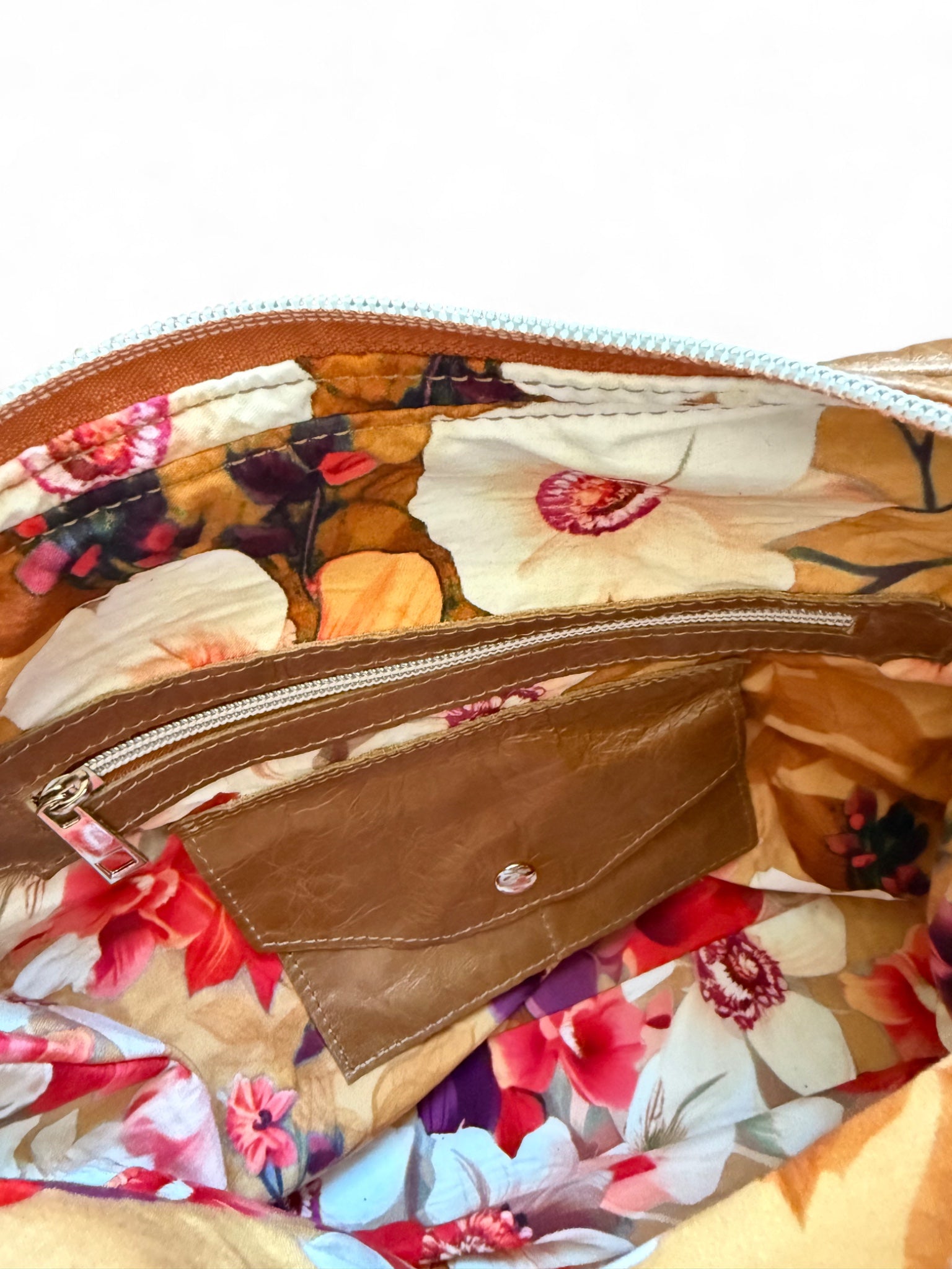 Floral-patterned bag with a brown leather pocket purse and zipper.