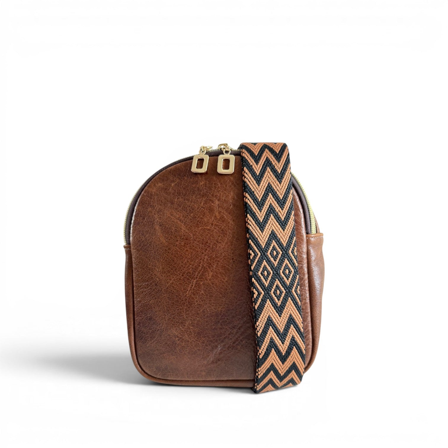 Compact, brown leather bag with a brown and black, chevron patterned strap on a white background