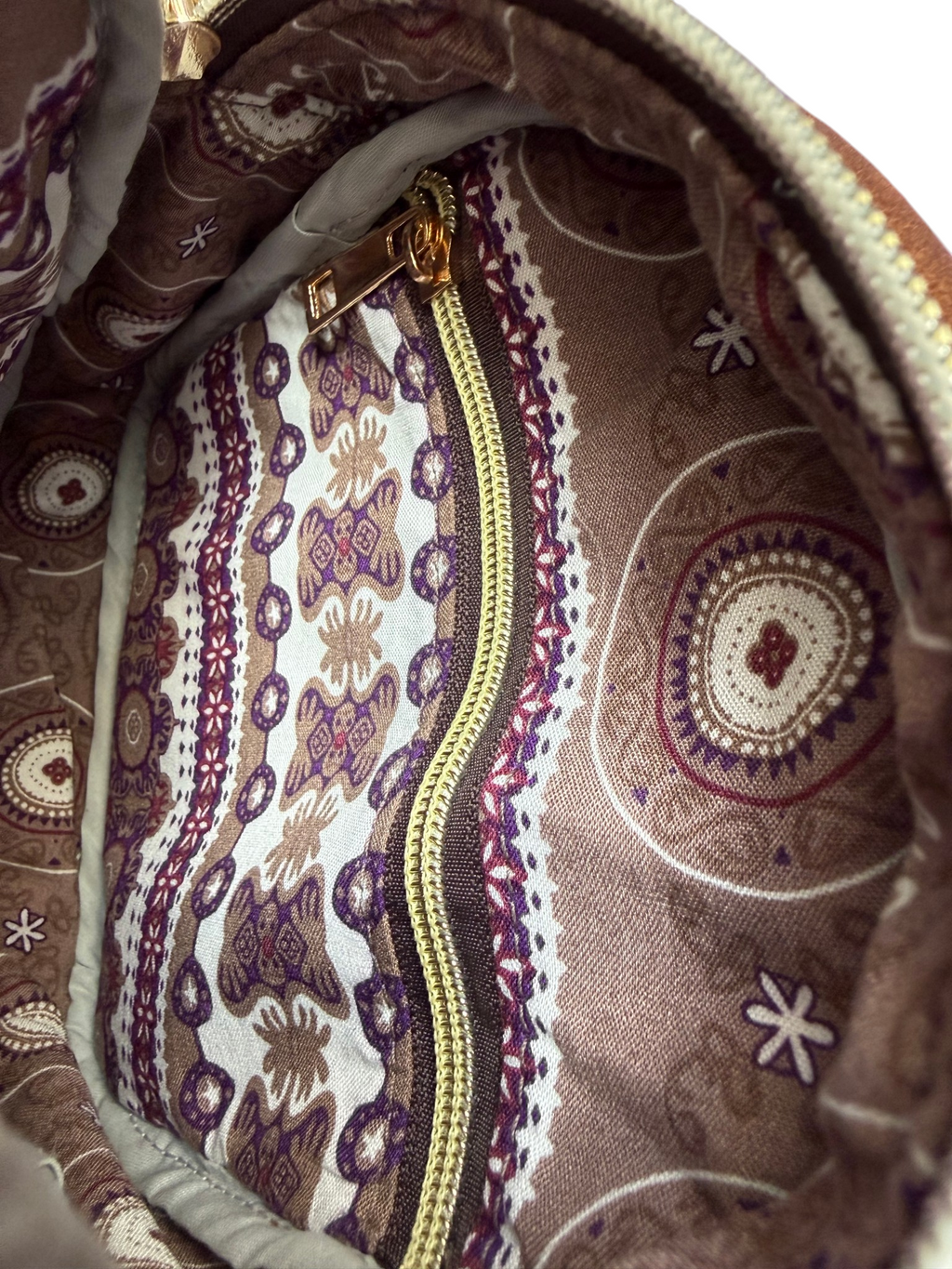 Close-up of the inside of the Maven crossbody sling bag, showing the patterned fabric lining and zipper pocket
