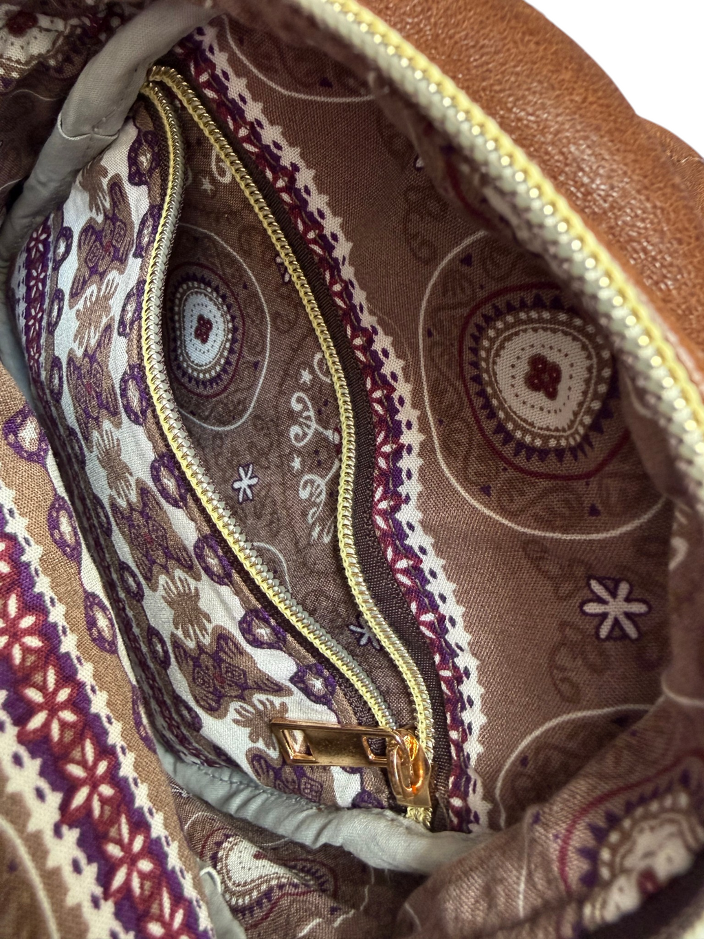 Close-up of a patterned fabric interior lining with an open zipper pocket, featuring intricate designs.