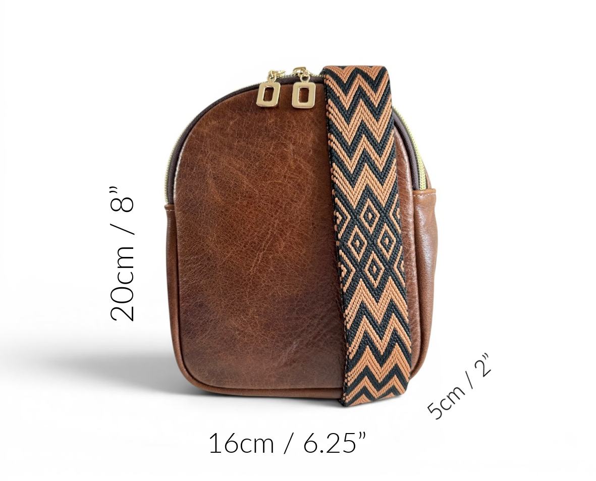 Small, brown leather crossbody sling bag with a patterned strap, showing measurements on a white background