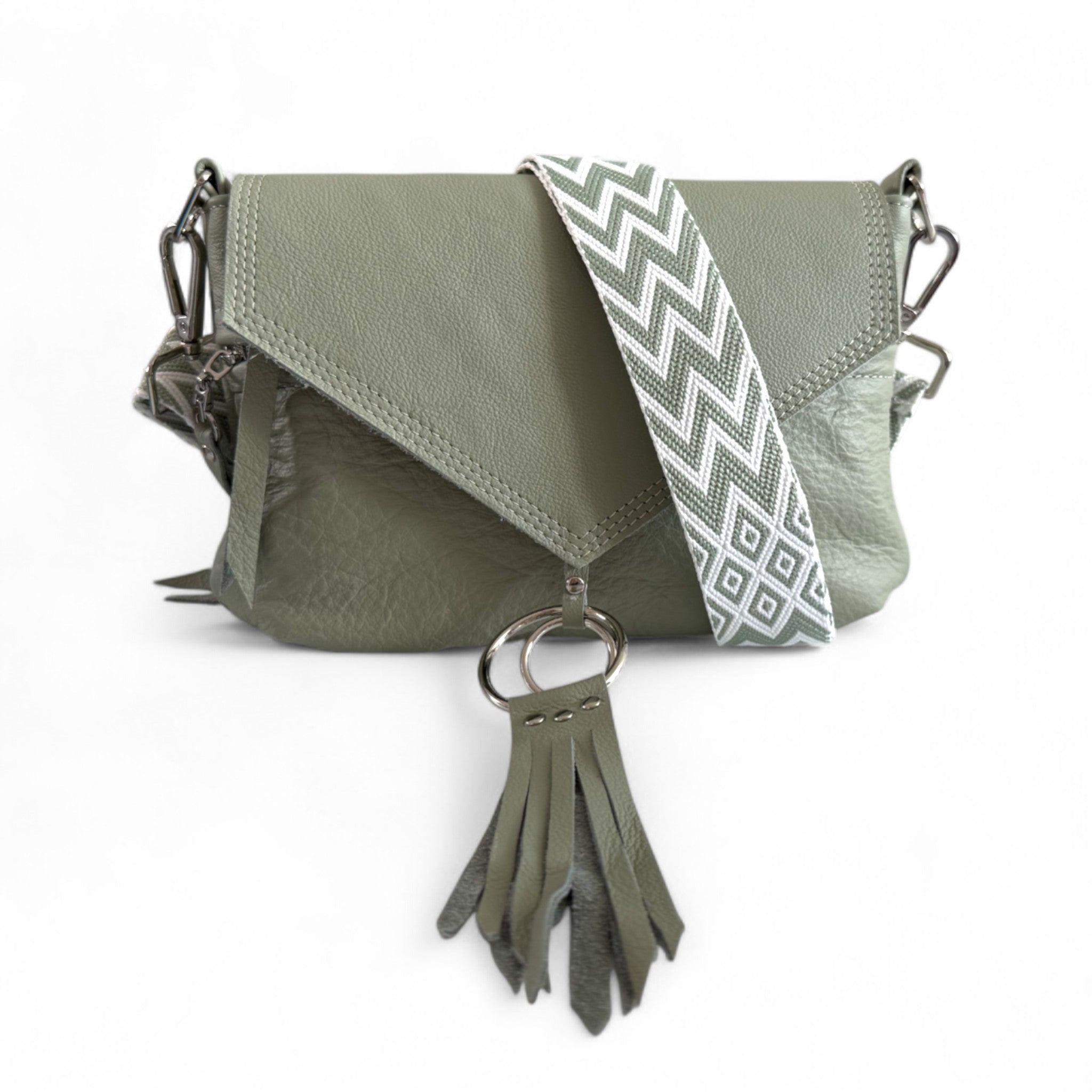 Light olive green leather handbag with a decorative. chevron patterned, adjustable, removable strap and tassel on a white background. 