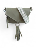Pale sage green leather crossbody handbag with a decorative strap and tassel on a white background.