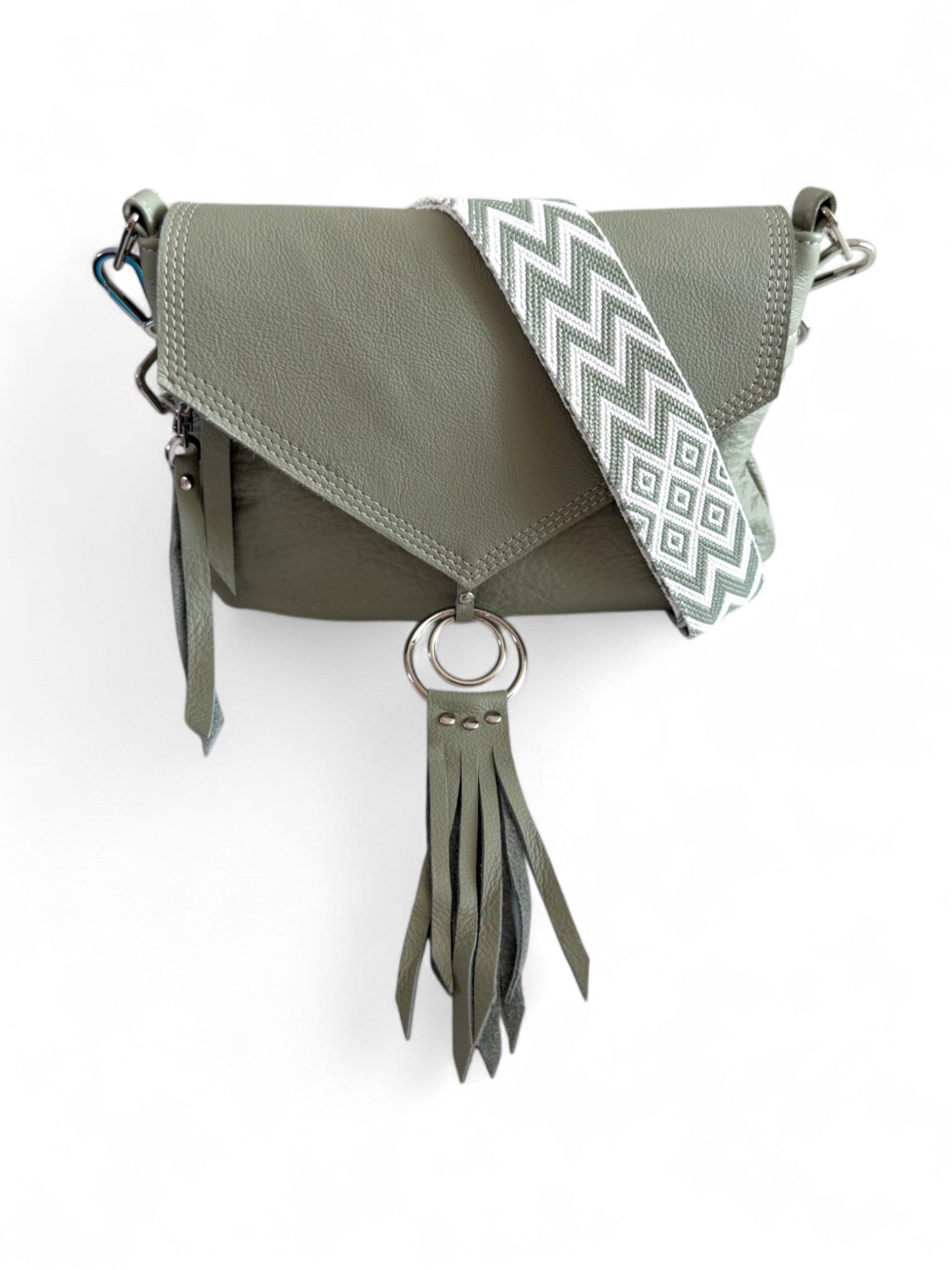 Pale sage green leather crossbody handbag with a decorative strap and tassel on a white background.