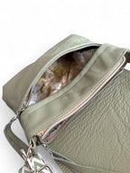 Light sage green leather handbag with an open front zippered pocket,showing the lining. 