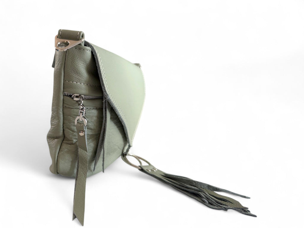 Side view of pale olive green soft leather bag and focusses on the silver hardware and tassels. 