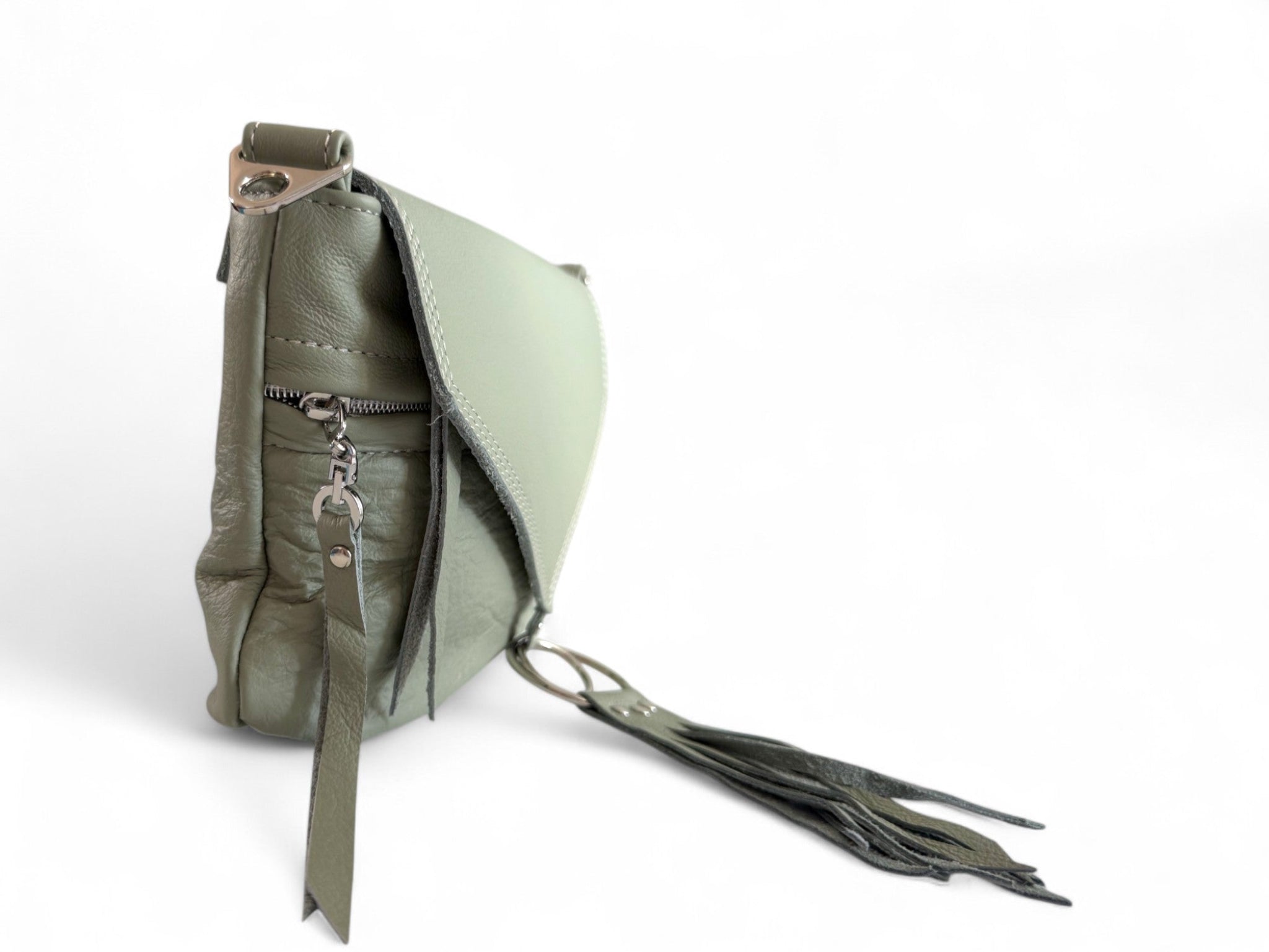 Side view of pale olive green soft leather bag and focusses on the silver hardware and tassels. 