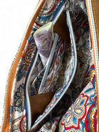 Inside view of the Olivia bag, showing the Paisley patterned lining, zipper pocket is open to reveal an integrated purse, containing cash, coins and bank card.