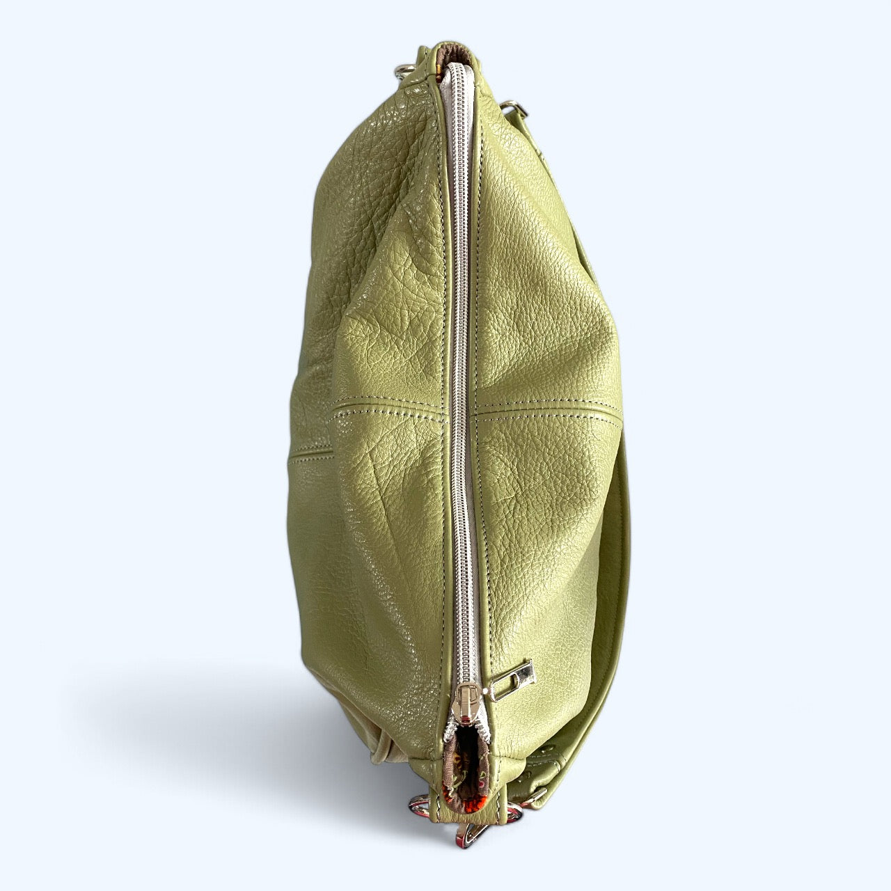 Birds Eye view of a pale green leather handbag with a silver zipper on a white background