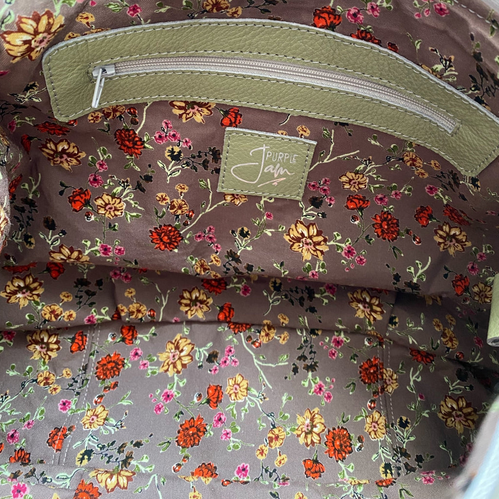 Floral-patterned lining of a bag with a green zipper pocket and logo label 