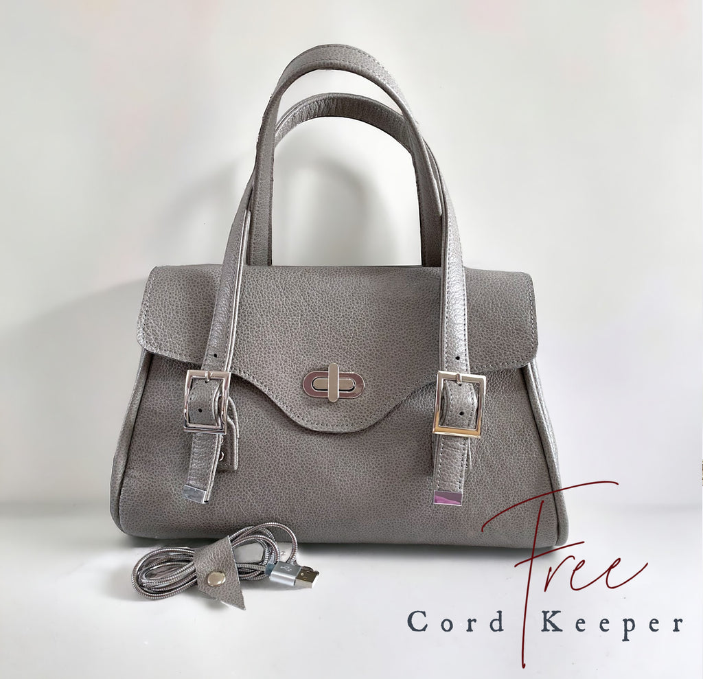 Grey leather handbag with USB cable and cord keeper on a white background
