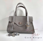 Grey leather handbag with USB cable and cord keeper on a white background