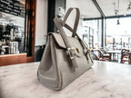 Grey rescued leather handbag with silver buckles and clasp on a coffee shop table