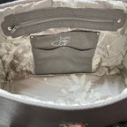 Interior view of a light grey leather handbag with silk interior slip pocket and Purple Jam logo 
