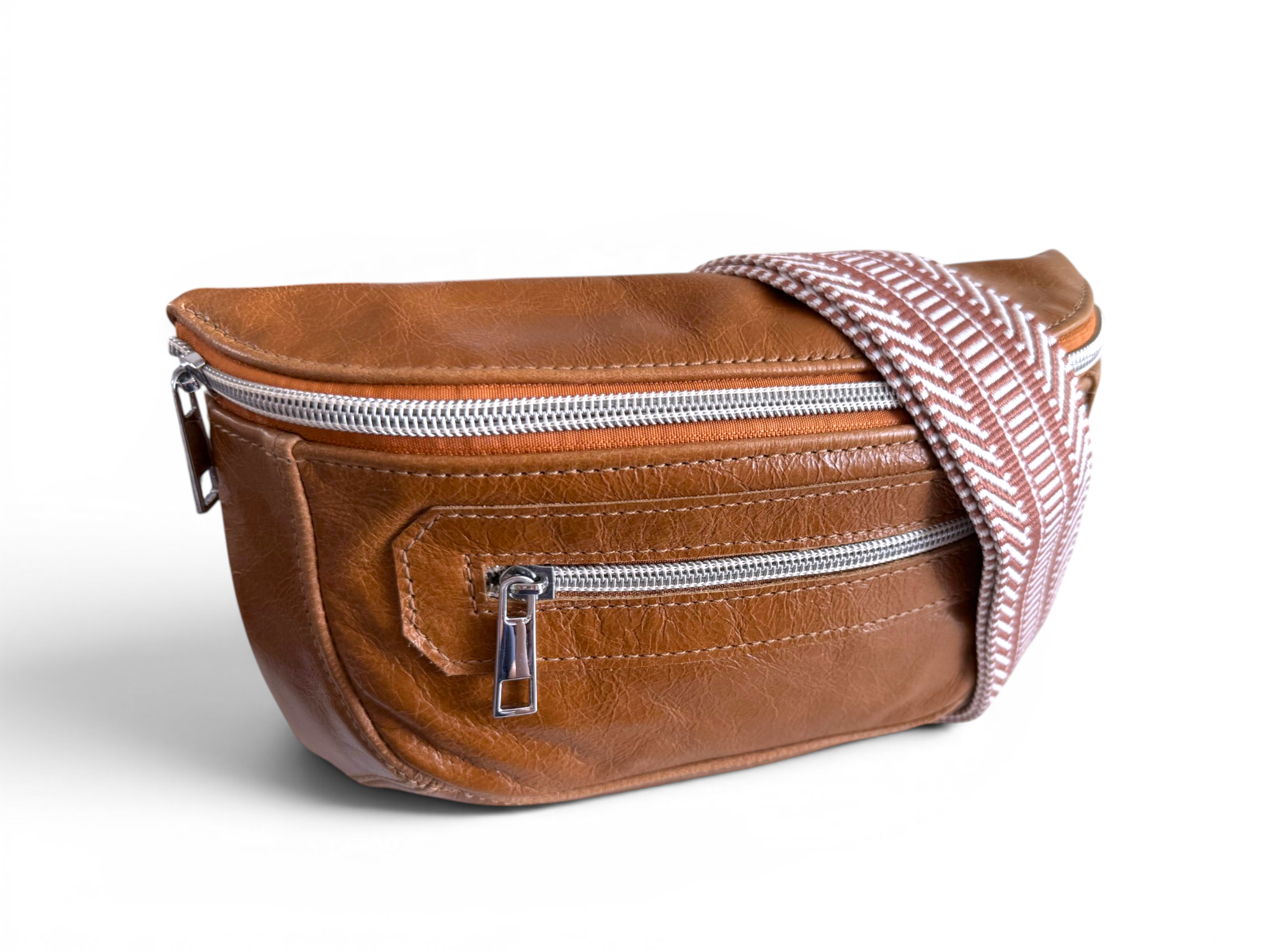 Tan brown leather waist bag with a tan and white patterned strap and silver zippers on a white background