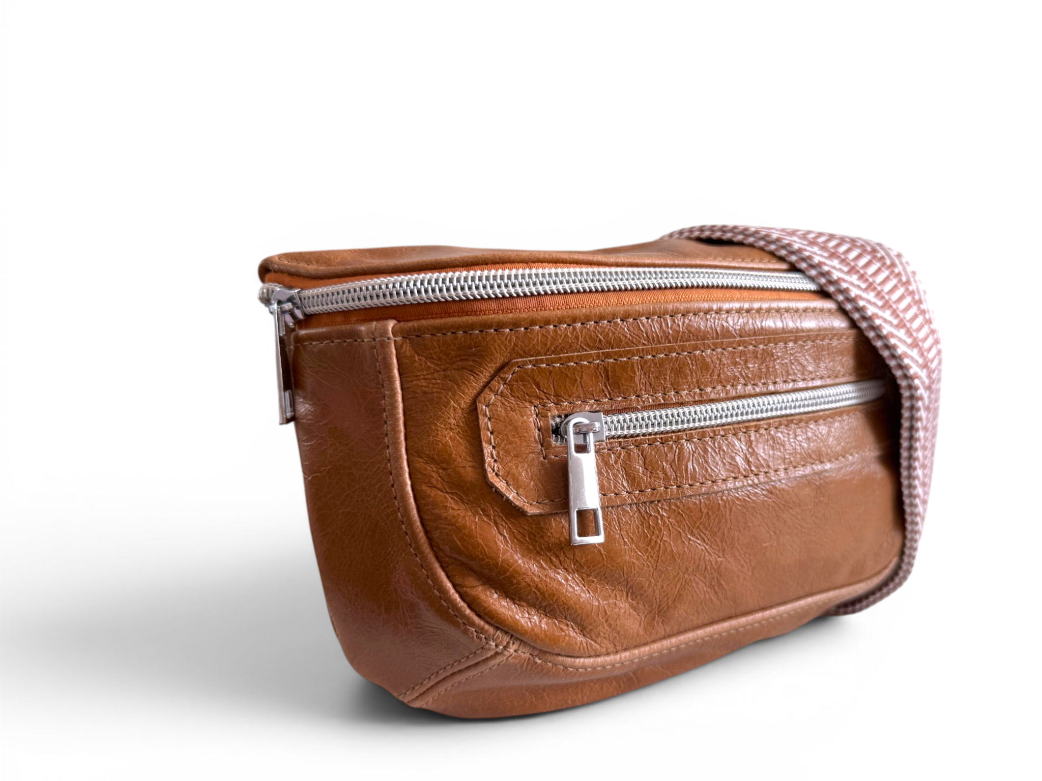 Tan brown leather multiway bag with silver zippers on a white background