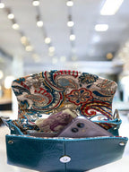Purse with paisley flap and blue body, contents visible, blurred interior background