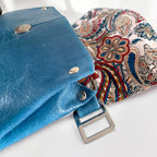 Blue leather bag with paisley fabric interior lining with silver hardwares on a white background