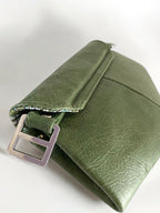 View of the back of a green, real leather clutch with metal buckle on white background