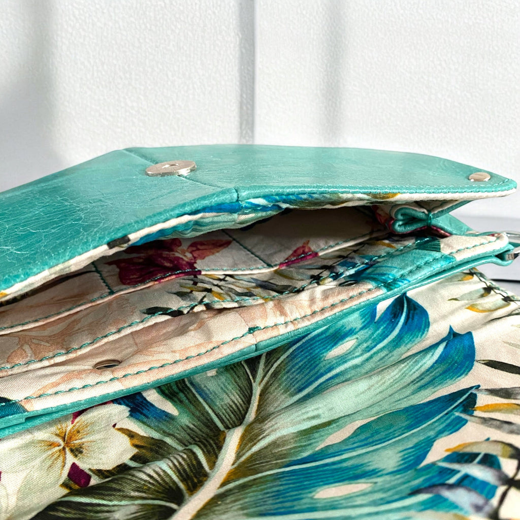 Floral-patterned fabric lining inside a turquoise leather crossbody bag.