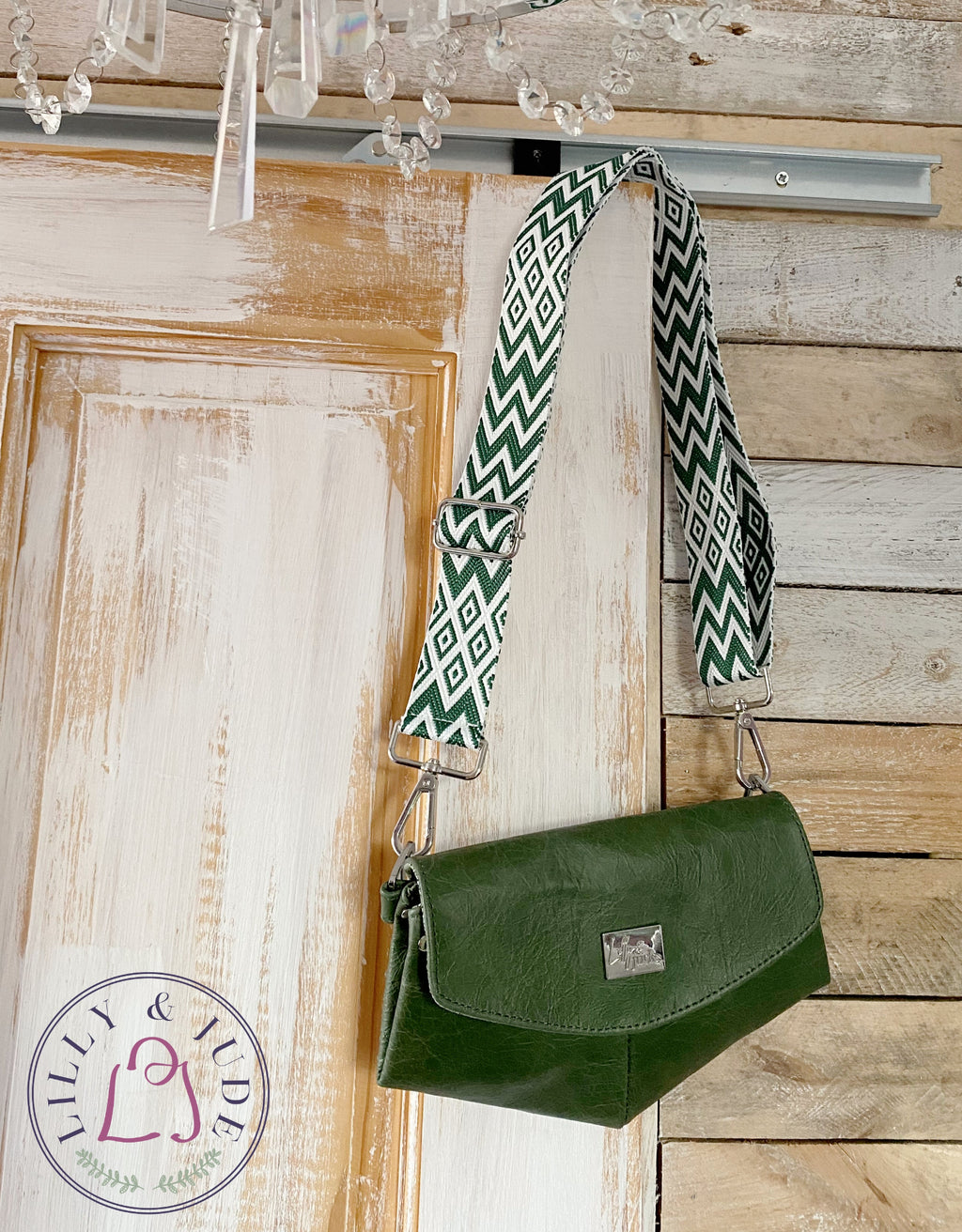 Green leather bag with a zigzag strap hanging on a wooden door.